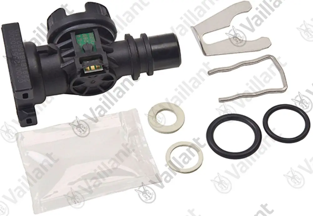 Vaillant Volumenstromsensor in Schwarz mit Anbauteilen, darunter Dichtungen, Halterung und eine transparente Verpackung. Verwendet in Heizungs- und Klimaanlagen.